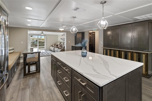 kitchen featuring dark brown cabinetry, hanging light fixtures, visible vents, and wood finished floors