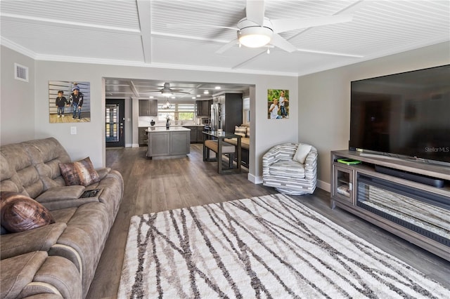 living area with a ceiling fan, baseboards, dark wood-style flooring, ornamental molding, and visible vents