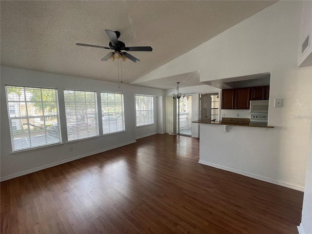 unfurnished living room featuring ceiling fan with notable chandelier, high vaulted ceiling, a textured ceiling, dark wood finished floors, and baseboards
