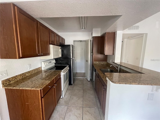 kitchen with a textured ceiling, white appliances, dark stone countertops, and visible vents