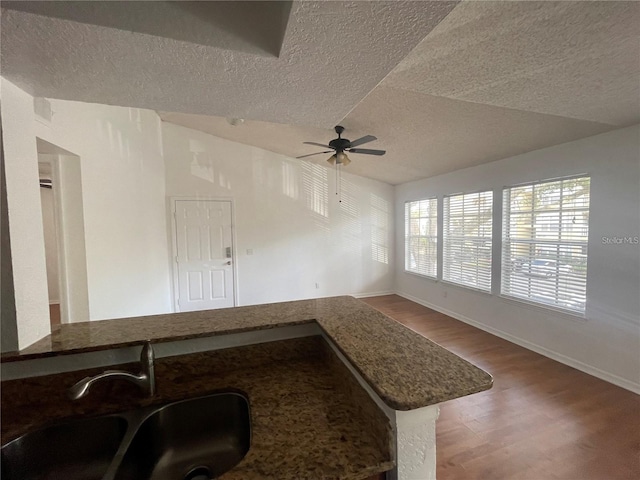 interior space with a textured ceiling, wood finished floors, ceiling fan, and a sink