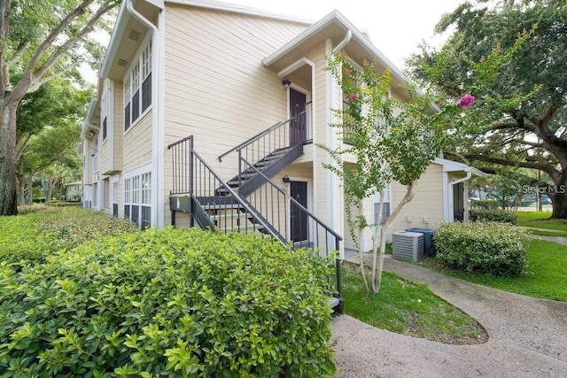 view of side of property with cooling unit and stairway