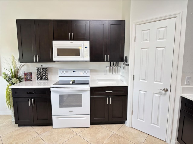 kitchen with light countertops, light tile patterned floors, dark brown cabinetry, and white appliances