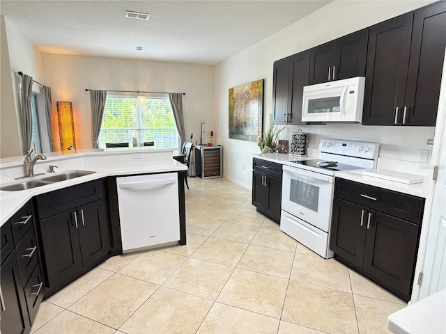 kitchen with light tile patterned flooring, a sink, white appliances, light countertops, and visible vents