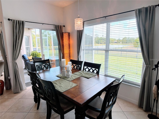 dining room featuring plenty of natural light, baseboards, light tile patterned floors, and an inviting chandelier