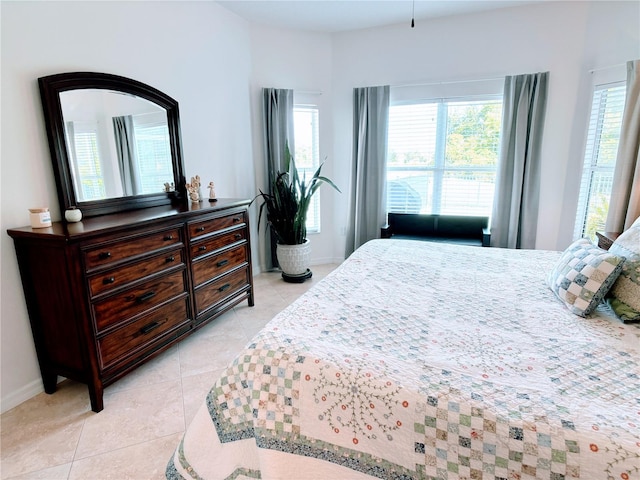 bedroom featuring baseboards, multiple windows, and light tile patterned floors