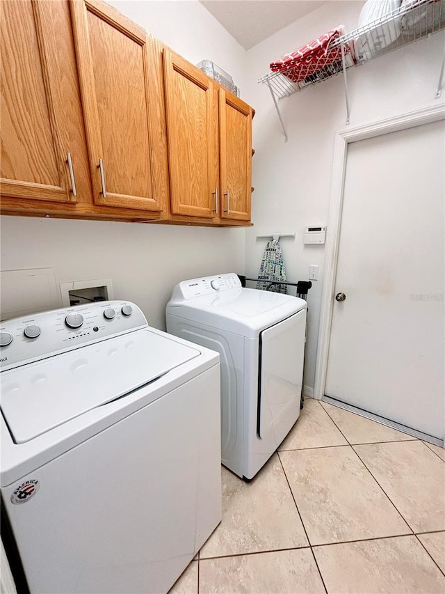 laundry area with cabinet space, light tile patterned flooring, and washer and dryer