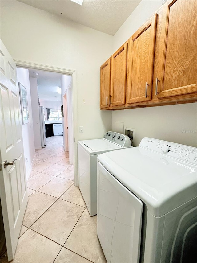 laundry area with light tile patterned floors, washing machine and dryer, and cabinet space
