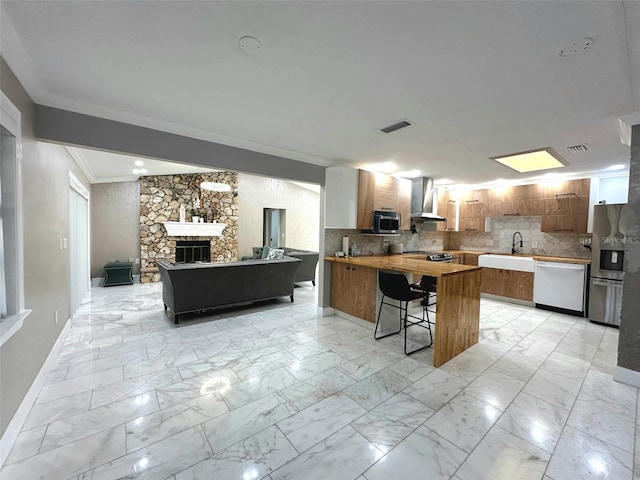 3328 Wax Berry Ct, Windermere, FL 34786 - kitchen with wall chimney range hood, appliances with stainless steel finishes, a peninsula, open floor plan, and ornamental molding
