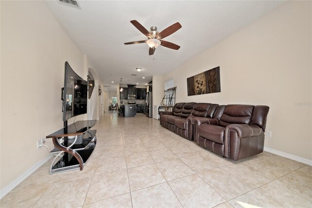 living room featuring visible vents, baseboards, ceiling fan, and light tile patterned floors