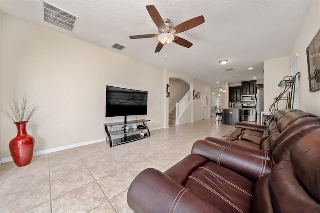living area featuring arched walkways, ceiling fan, light tile patterned flooring, and visible vents