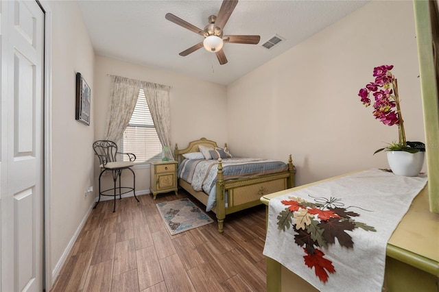 bedroom featuring ceiling fan, baseboards, visible vents, and wood finished floors
