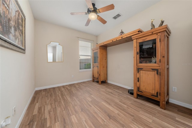 spare room with ceiling fan, visible vents, baseboards, and light wood finished floors