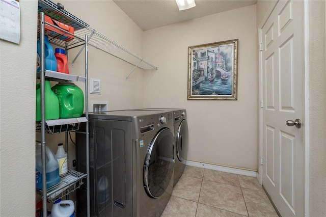 washroom with laundry area, washing machine and dryer, baseboards, and tile patterned floors