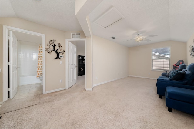 living area with visible vents, a textured ceiling, and light carpet