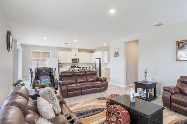 living area with visible vents, recessed lighting, light wood finished floors, and baseboards