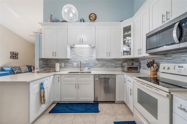 98 Lakepointe Cir, Kissimmee, FL 34743 - kitchen featuring tasteful backsplash, white cabinets, a sink, appliances with stainless steel finishes, and a peninsula