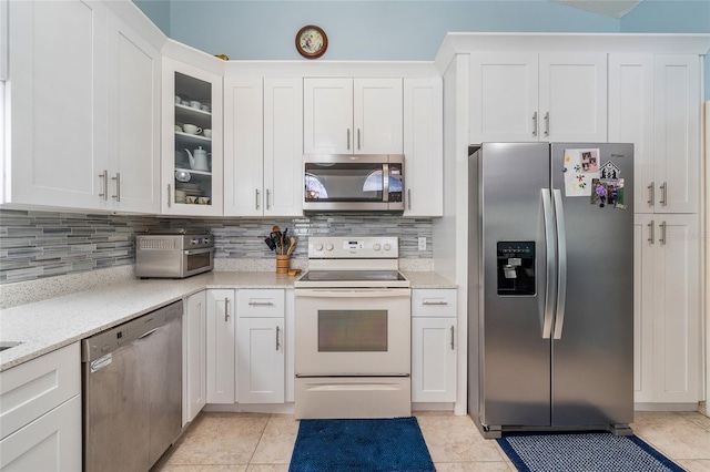 98 Lakepointe Cir, Kissimmee, FL 34743 - kitchen with white cabinets, glass insert cabinets, appliances with stainless steel finishes, light tile patterned flooring, and backsplash