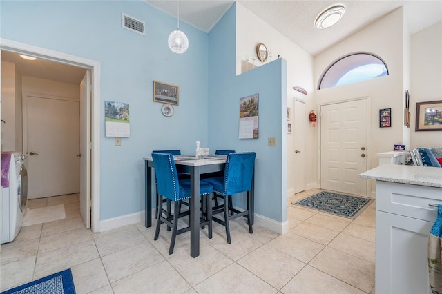 98 Lakepointe Cir, Kissimmee, FL 34743 - dining room with light tile patterned floors, baseboards, visible vents, washer / clothes dryer, and high vaulted ceiling