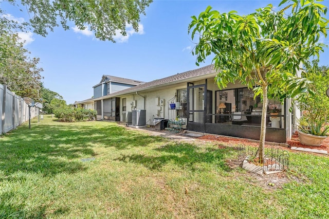 98 Lakepointe Cir, Kissimmee, FL 34743 - back of house featuring a sunroom, fence, a lawn, and central AC unit
