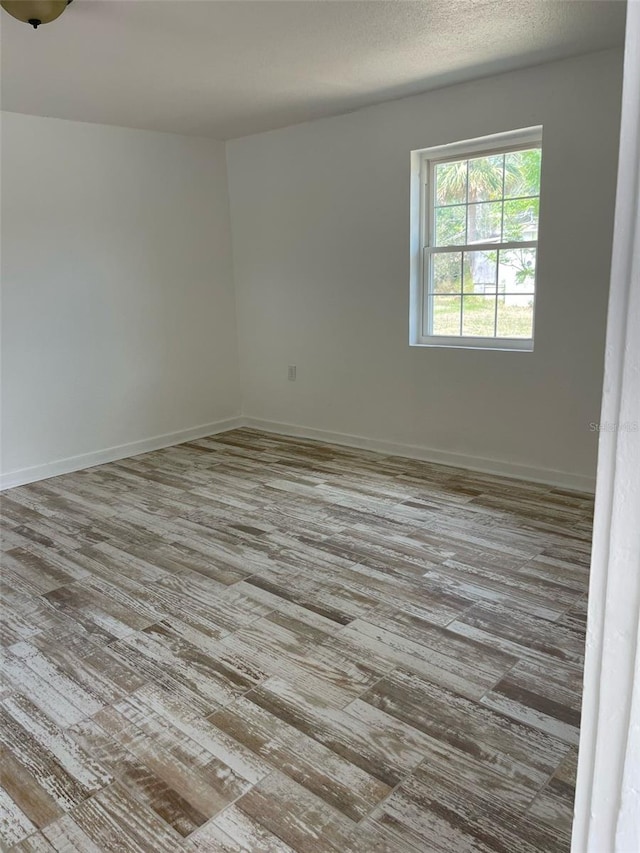 spare room featuring baseboards and wood finished floors