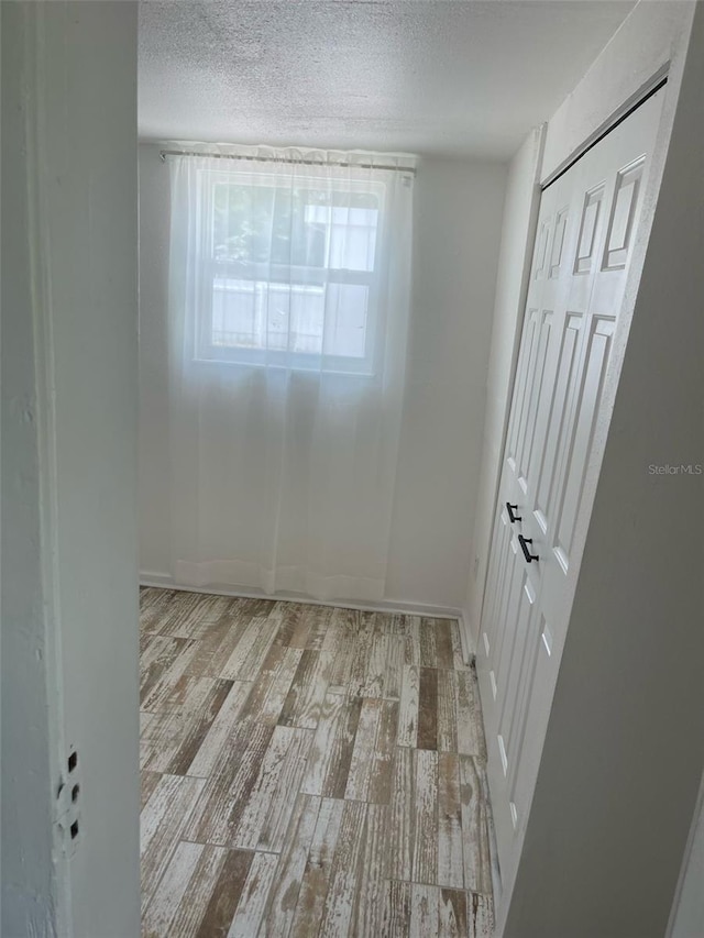 empty room featuring baseboards, a textured ceiling, and wood finished floors