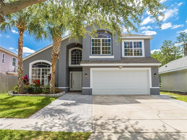 traditional home with fence, a garage, driveway, and stucco siding