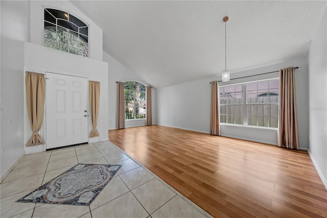 foyer featuring baseboards, light tile patterned floors, and high vaulted ceiling