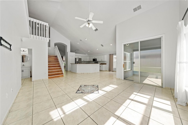 unfurnished living room with ceiling fan, arched walkways, high vaulted ceiling, visible vents, and stairway