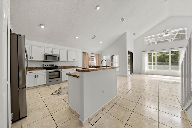 kitchen with light tile patterned flooring, dark countertops, ceiling fan, white cabinets, and appliances with stainless steel finishes