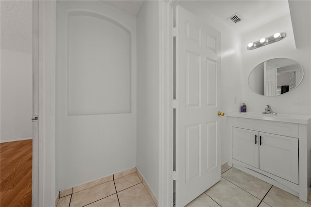 bathroom featuring baseboards, visible vents, tile patterned floors, and vanity