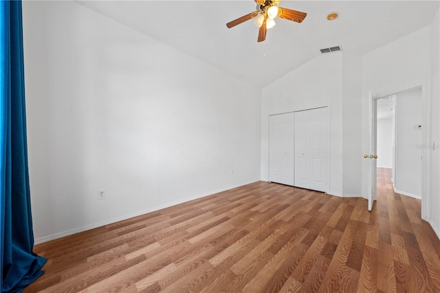 unfurnished bedroom featuring a closet, lofted ceiling, light wood finished floors, and visible vents