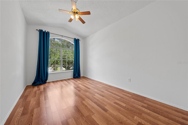 spare room with ceiling fan, a textured ceiling, baseboards, lofted ceiling, and light wood-type flooring