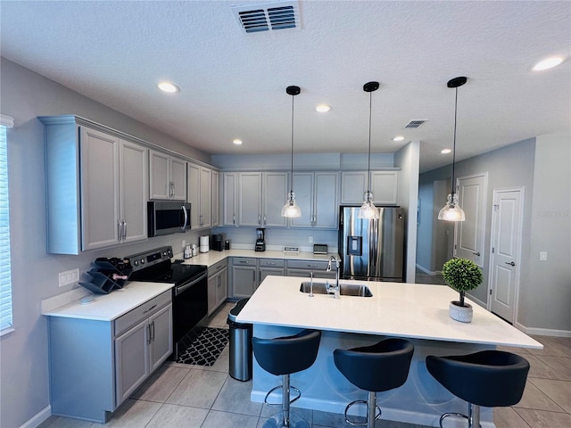 1321 Yorkdale Rd, Davenport, FL 33837 - kitchen featuring a breakfast bar area, light countertops, gray cabinets, a sink, and stainless steel appliances