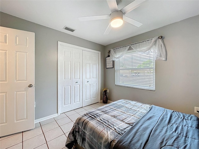 bedroom featuring ceiling fan, baseboards, light tile patterned floors, visible vents, and a closet