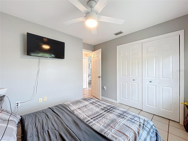 bedroom with a ceiling fan, visible vents, light tile patterned floors, and a closet