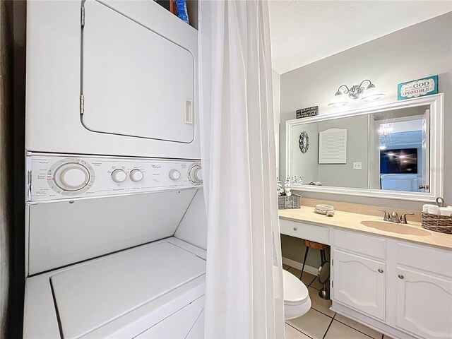 bathroom with stacked washer and dryer, tile patterned flooring, and vanity