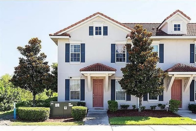 townhome / multi-family property with a tiled roof and stucco siding