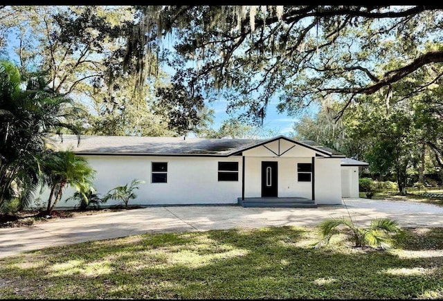 single story home with stucco siding and a front yard