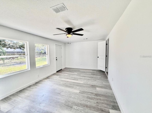 spare room featuring a textured ceiling, ceiling fan, wood finished floors, and visible vents
