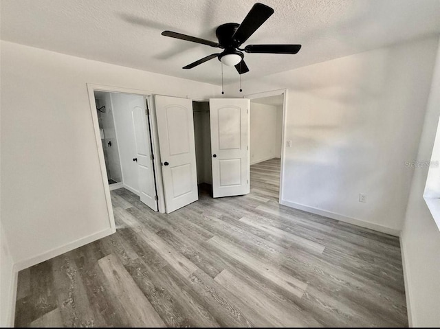unfurnished bedroom with baseboards, a ceiling fan, a textured ceiling, and wood finished floors