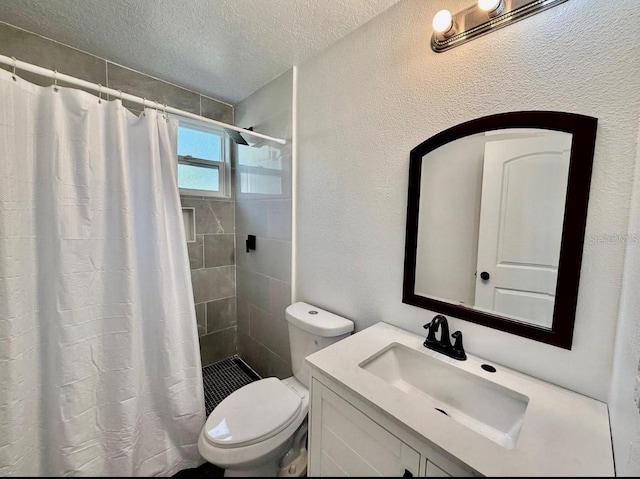 bathroom featuring a textured ceiling, vanity, toilet, a textured wall, and tiled shower
