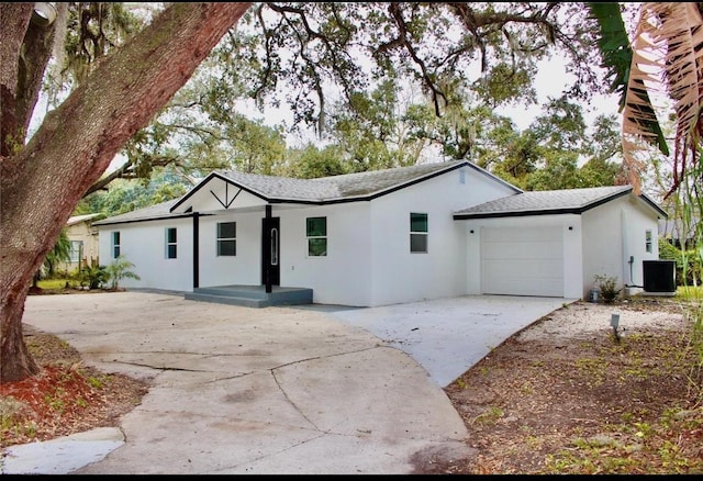 ranch-style house with a garage, cooling unit, stucco siding, and concrete driveway