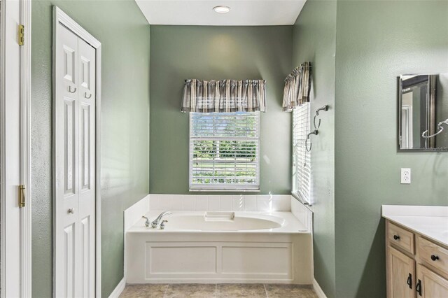 759 Glendora Rd, Kissimmee, FL 34759 - bathroom featuring a garden tub, vanity, a closet, tile patterned floors, and baseboards
