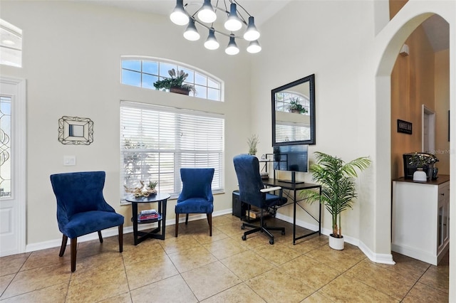 office featuring a towering ceiling, baseboards, arched walkways, light tile patterned floors, and a notable chandelier