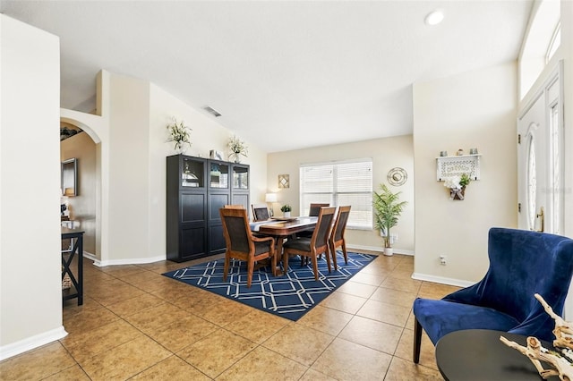 tiled dining room featuring arched walkways, baseboards, and visible vents