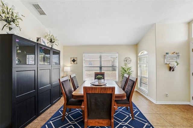 dining space with baseboards, a textured ceiling, visible vents, and light tile patterned floors