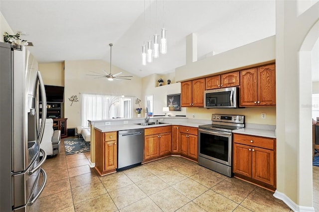 kitchen featuring a peninsula, a sink, appliances with stainless steel finishes, and brown cabinets
