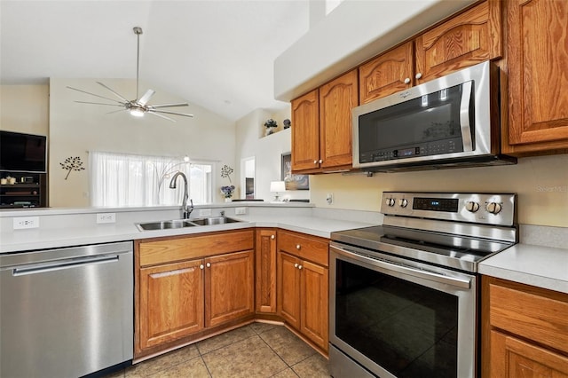 kitchen with ceiling fan, appliances with stainless steel finishes, a sink, light countertops, and brown cabinetry
