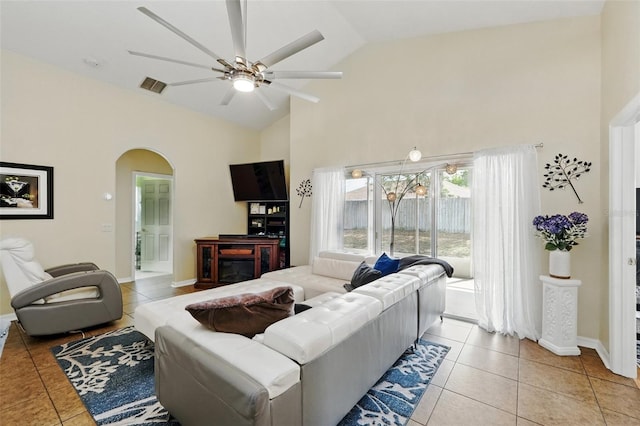 living room with arched walkways, ceiling fan, light tile patterned floors, and high vaulted ceiling